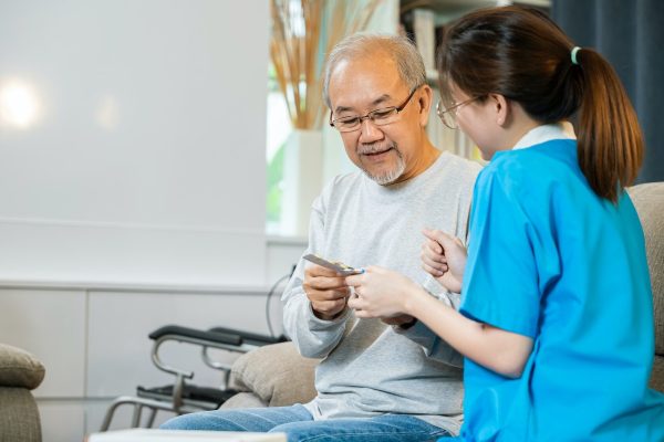 woman-nurse-caregiver-showing-prescription-drug-to-senior-man-at-nursing-home